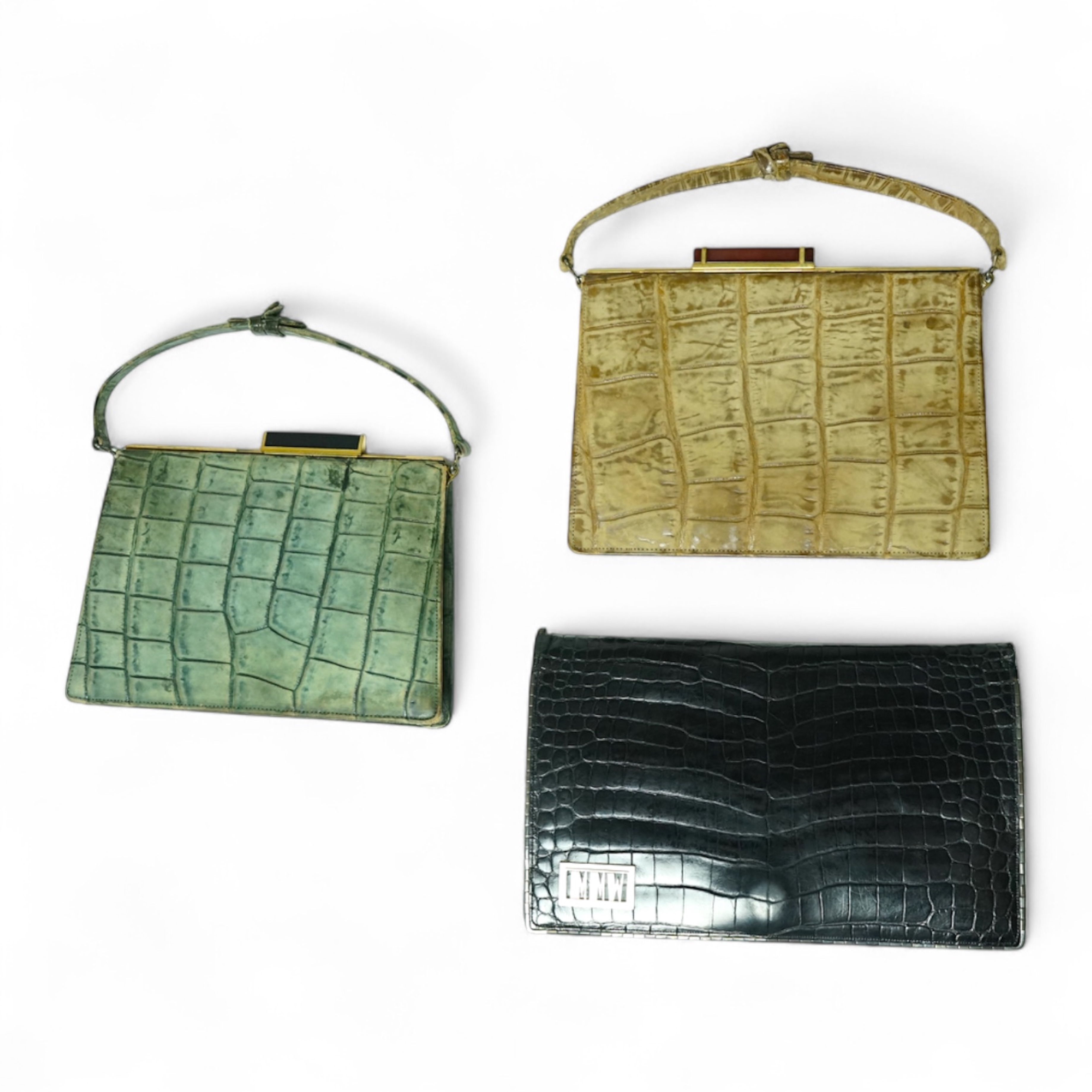 Three stylish Art Deco ladies handbags. A black crocodile clutch bag with an MMW monogram and silver mounted edge and two smaller handbags, one green the other brown, both faux crocodile with stylish bakelite clasps. Clu